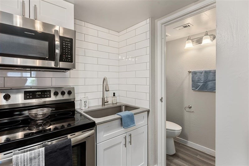 A kitchen with a black stove top oven and a black microwave above it.