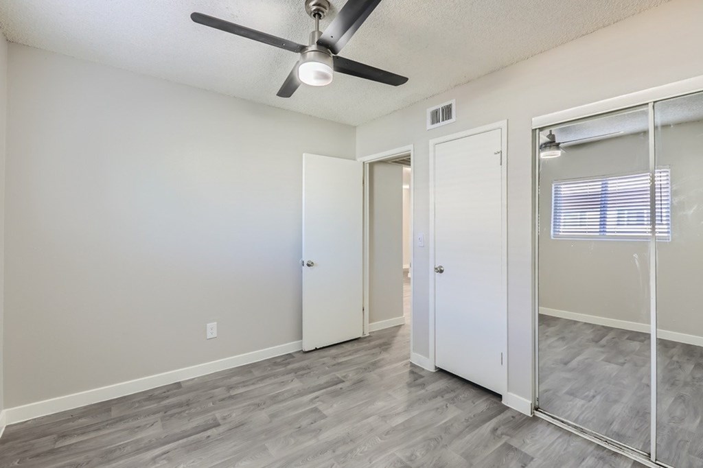 A room with a ceiling fan and a glass door.