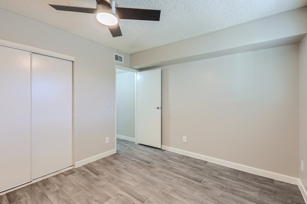 A room with a ceiling fan and a door.