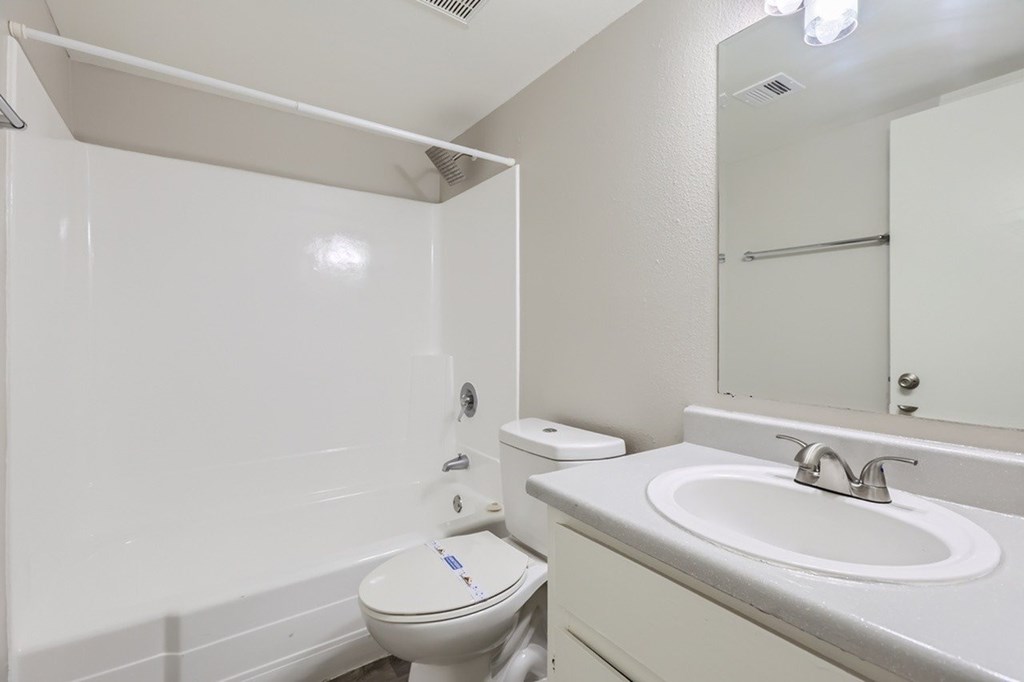 A white toilet with a white towel rack and a white sink with a silver faucet.