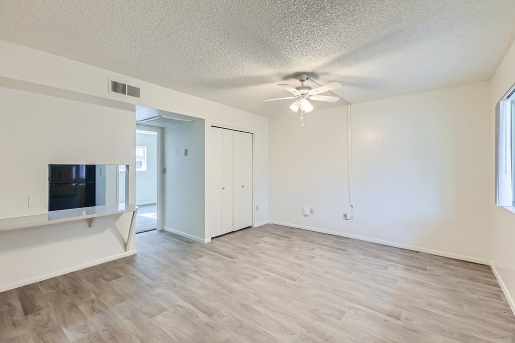 A spacious room with a ceiling fan and lighting fixture.