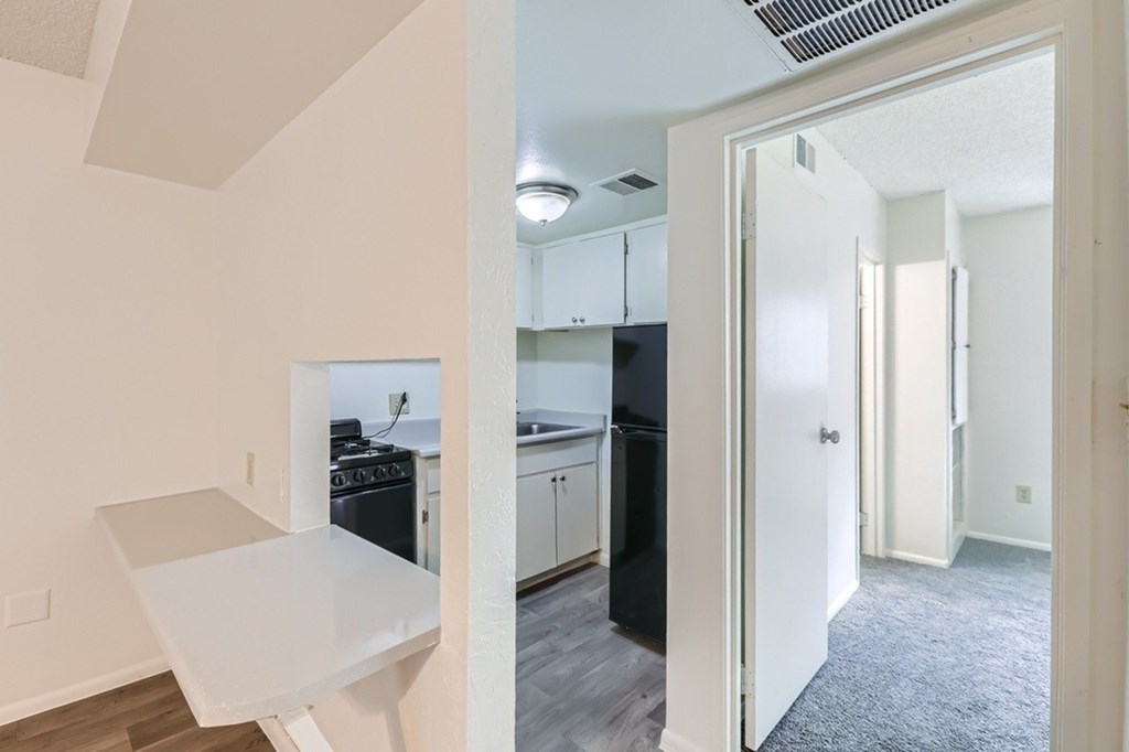 A kitchen with a white countertop and a black refrigerator.