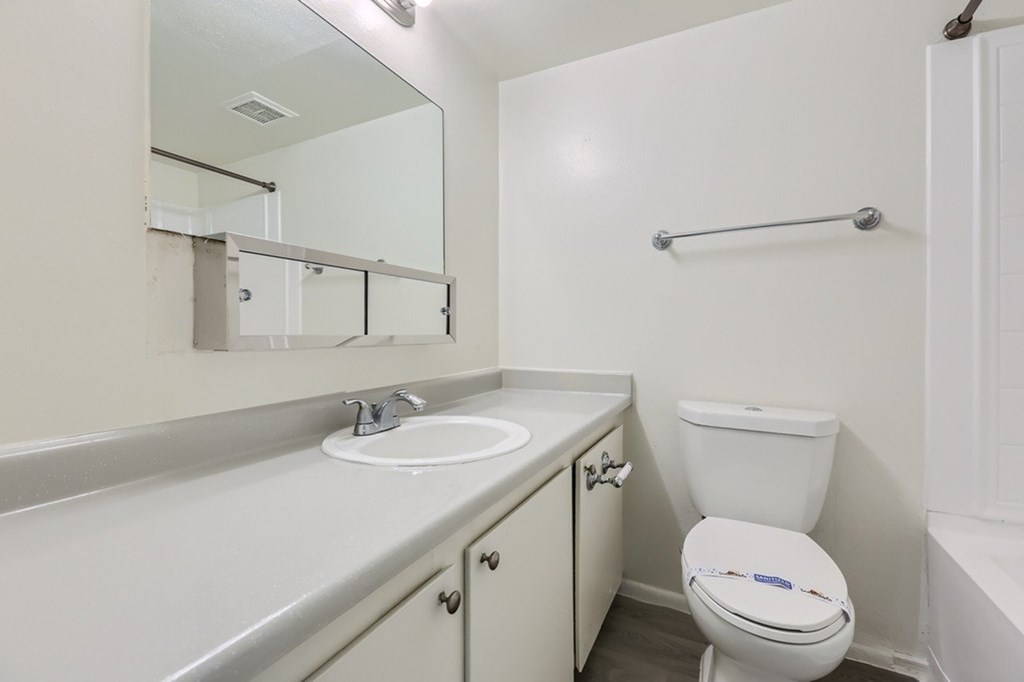 A white bathroom with a toilet, sink, and mirror.