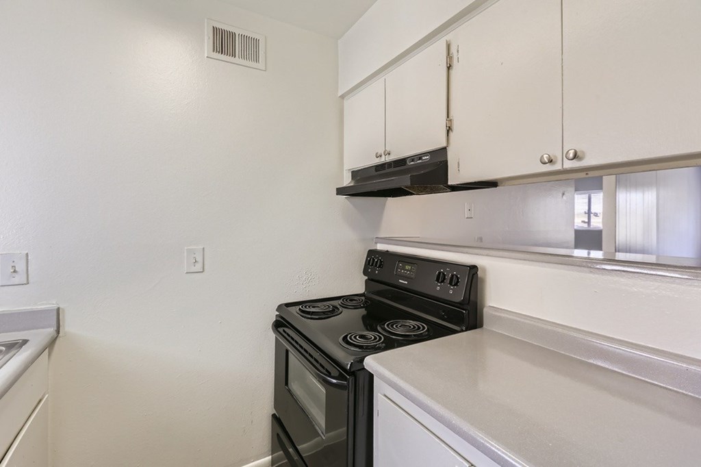 A kitchen with a black stove and white cabinets.