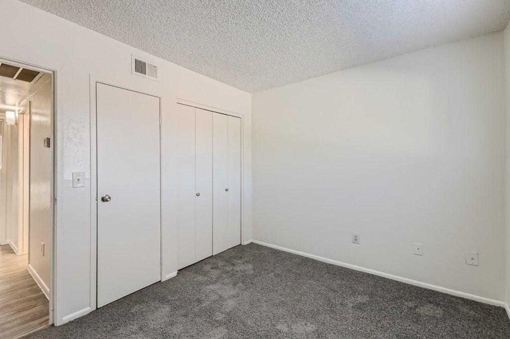 A room with white walls and a grey carpet.