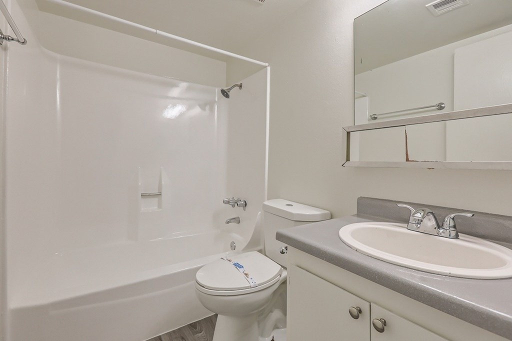 A white toilet with a white bath tub in a bathroom.