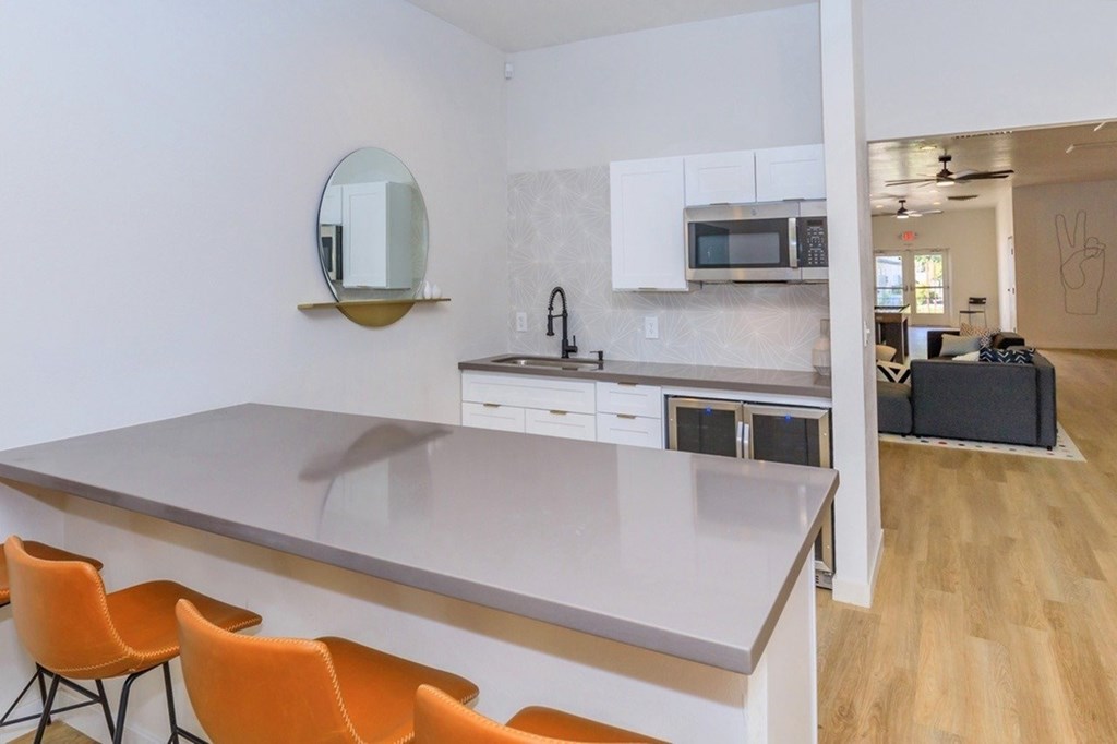A modern kitchen with orange chairs and a large island.