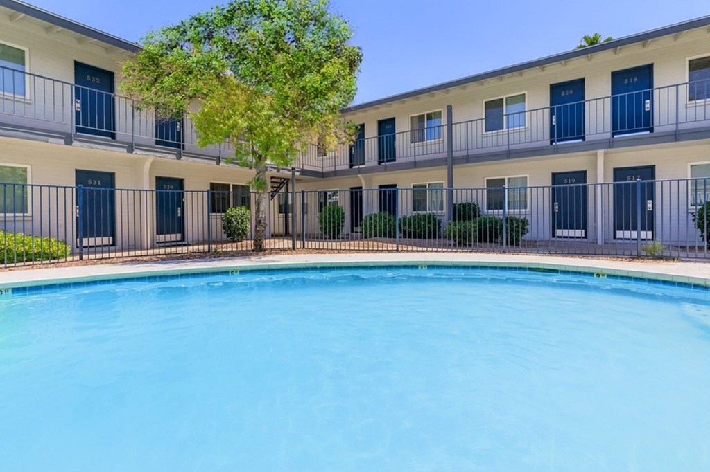 A swimming pool in front of a building with balconies.