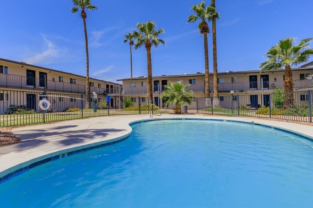 A swimming pool surrounded by palm trees and apartment buildings.