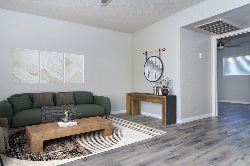 A living room with a green couch, wooden coffee table, and a rug.