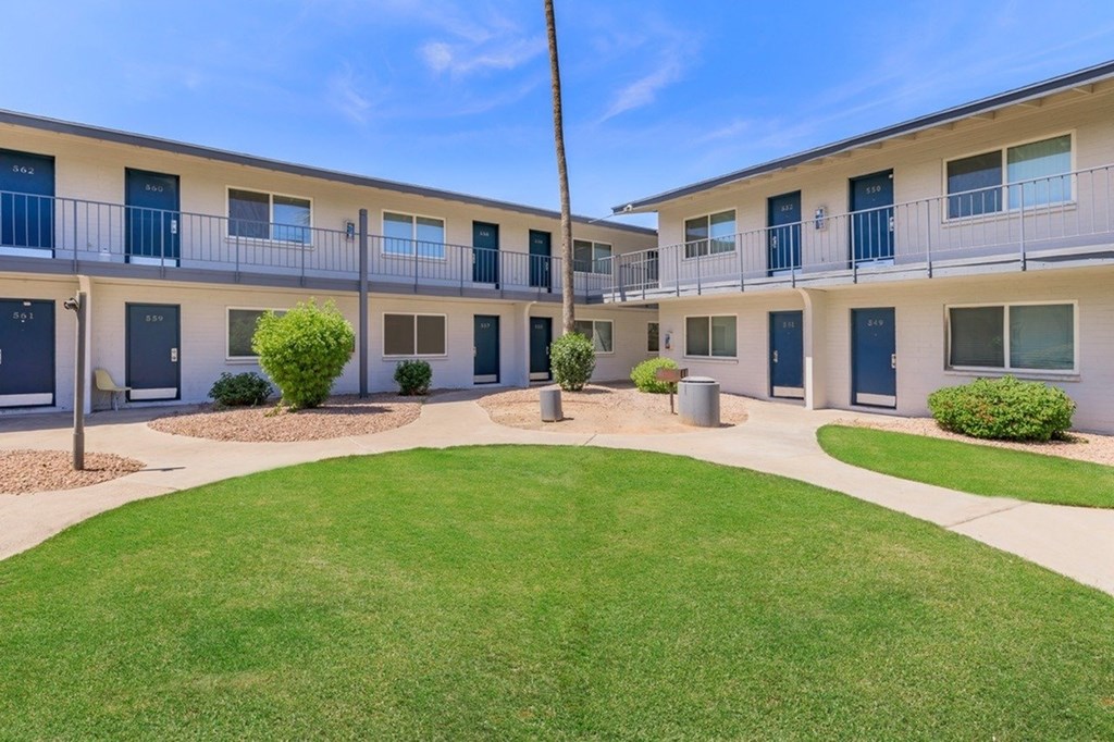 A sunny day at a well-kept apartment complex with green lawns and blue doors.