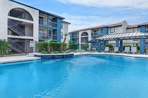 A large swimming pool in front of apartment buildings.