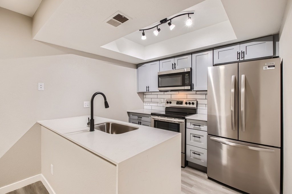A modern kitchen with stainless steel appliances and a white countertop.