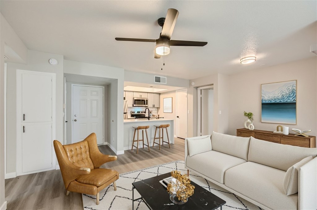 A living room with a brown chair, a white couch, and a black coffee table.