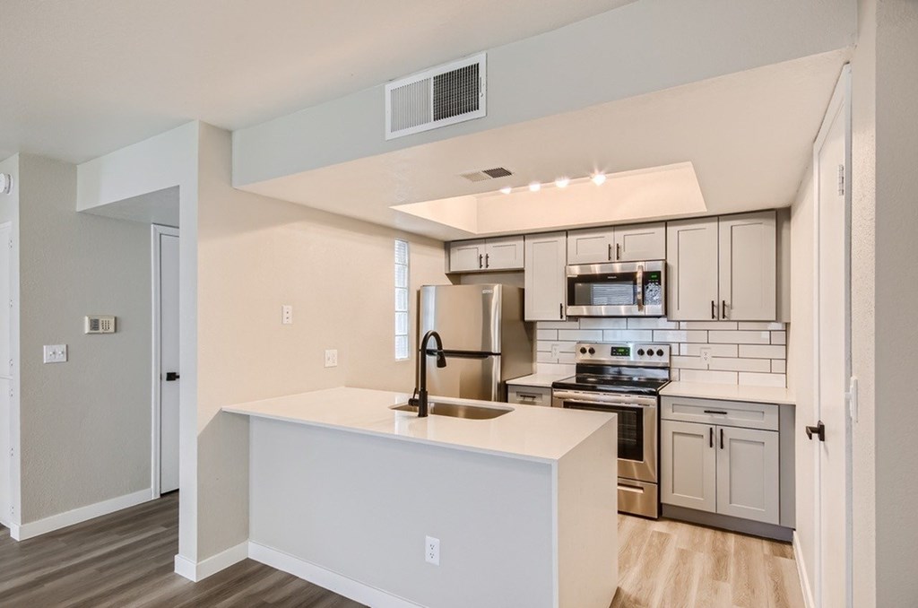 A kitchen with a white island and stainless steel appliances.