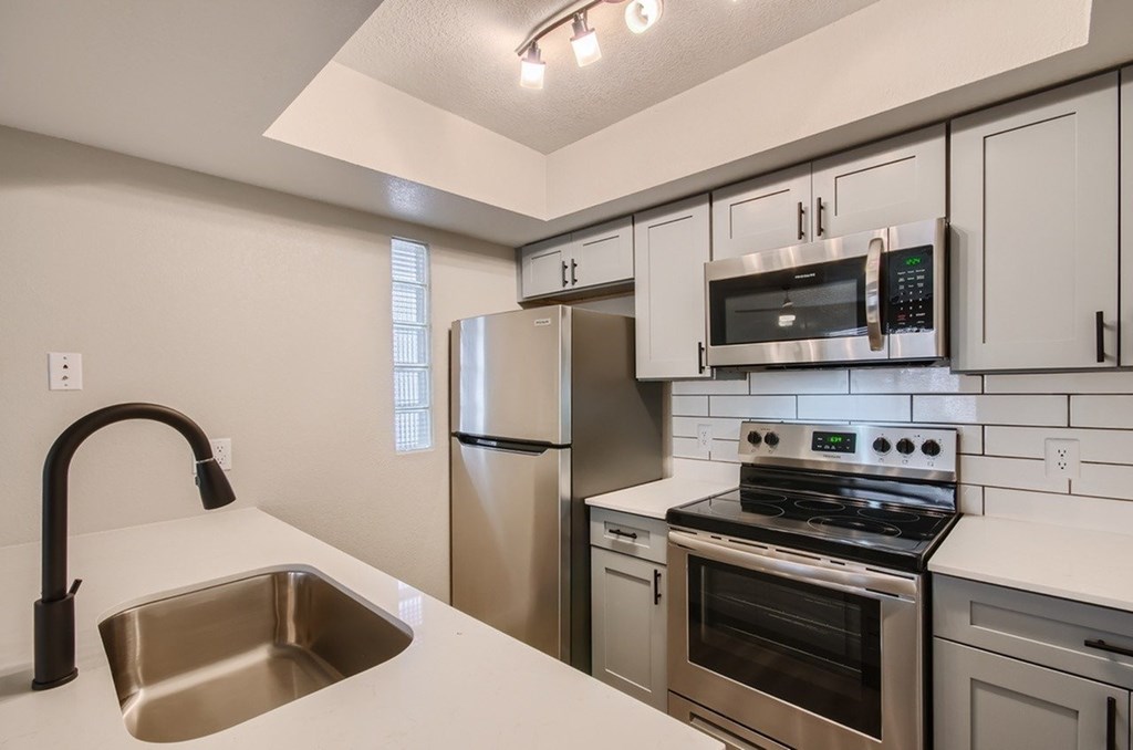 A modern kitchen with stainless steel appliances and white countertops.