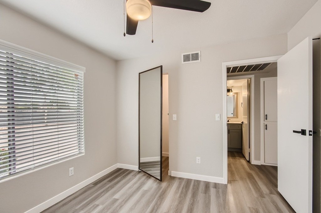 A room with a ceiling fan and a large mirror.