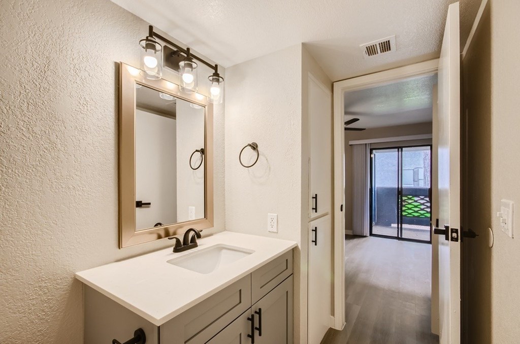 A bathroom with a sink, mirror, and lights.