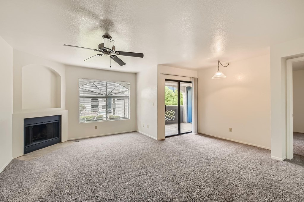 A living room with a fireplace and a ceiling fan.