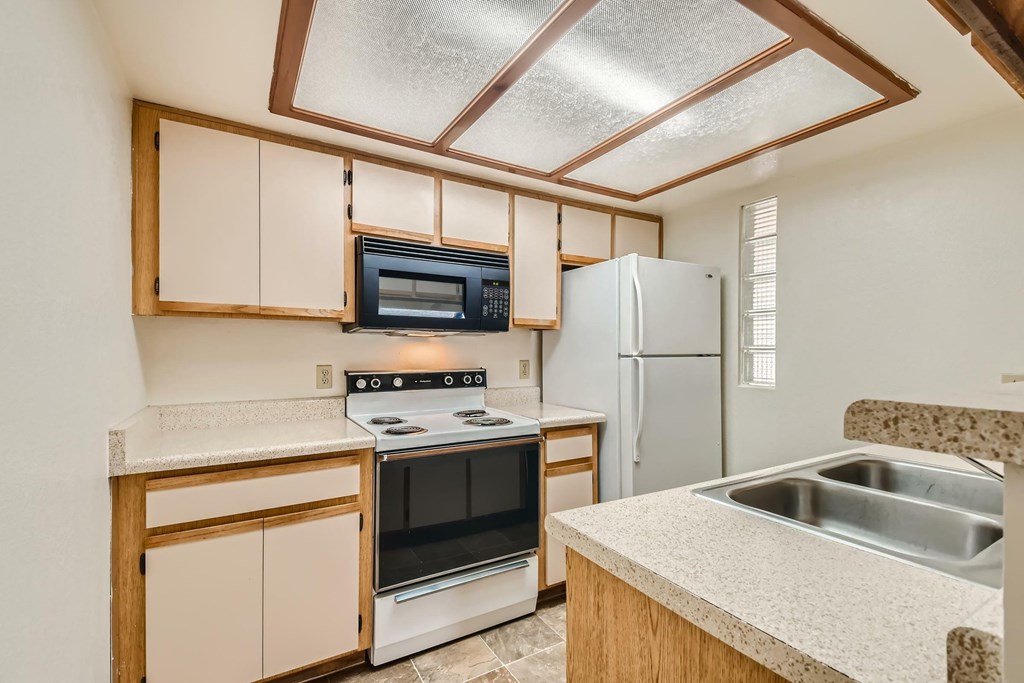 A kitchen with a stove, oven, microwave, refrigerator, and sink.