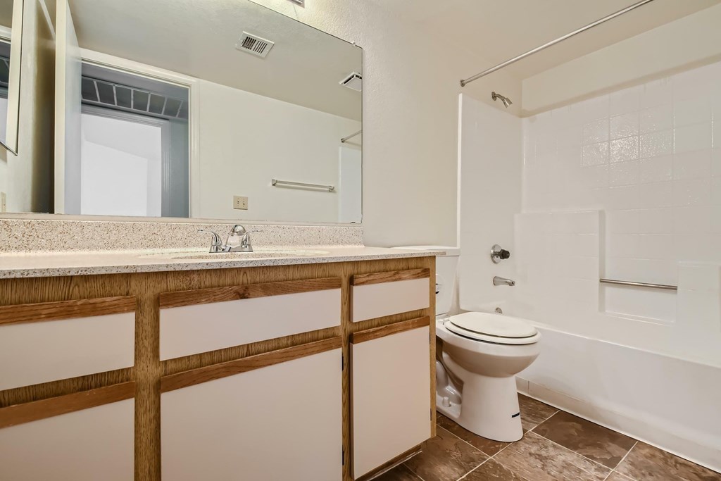 A white toilet sits in a bathroom with a wooden counter.