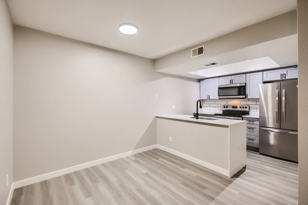 A kitchen with a stainless steel refrigerator and a microwave above the stove.