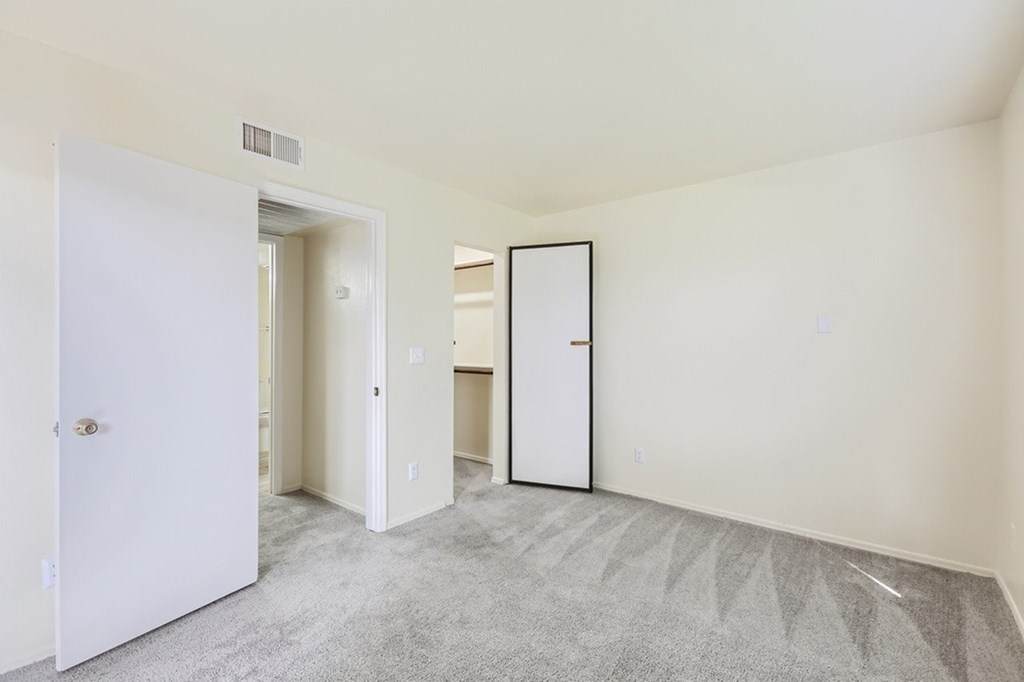 A white door is open to a hallway with a carpeted floor.