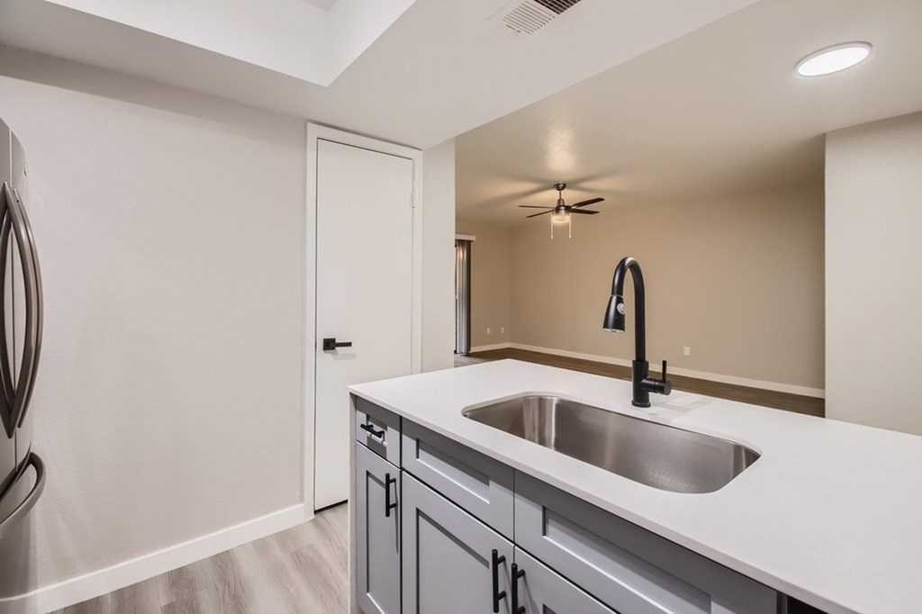 A modern kitchen with a white countertop and a stainless steel sink.