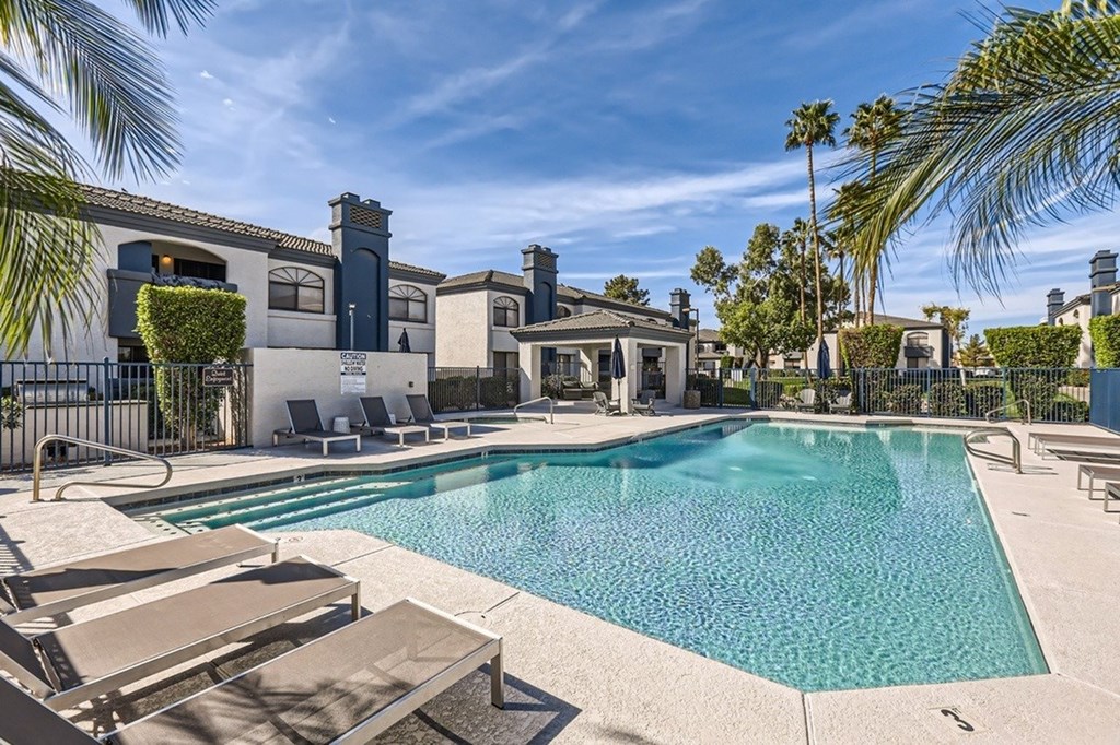 A large swimming pool surrounded by lounge chairs and palm trees.