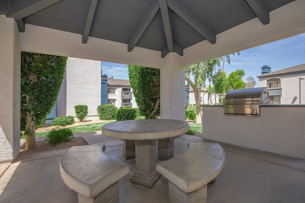 A patio with a table and two chairs under a roof.