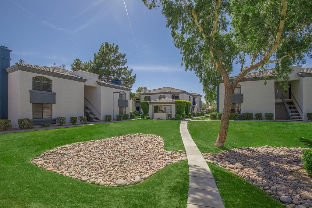 A sunny day in a residential area with houses and a stone pathway.