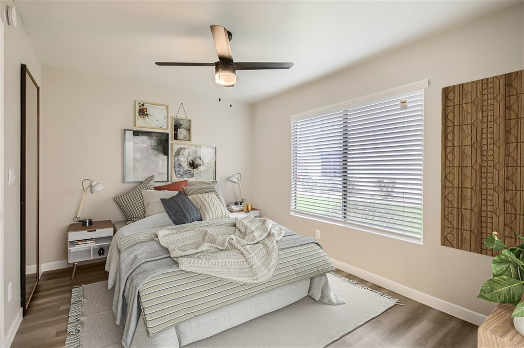 A bedroom with a bed, a ceiling fan, and a window with blinds.