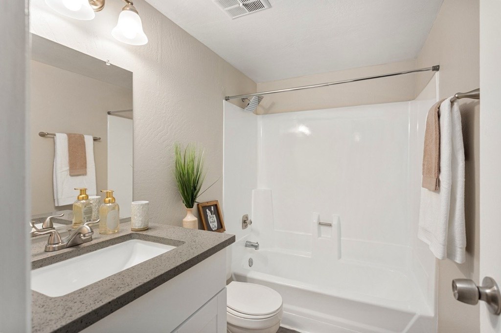 A bathroom with a white toilet, sink, and bathtub.