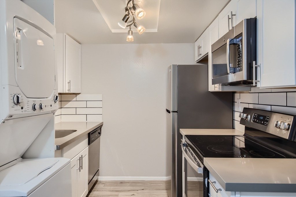 A kitchen with white cabinets and black appliances.