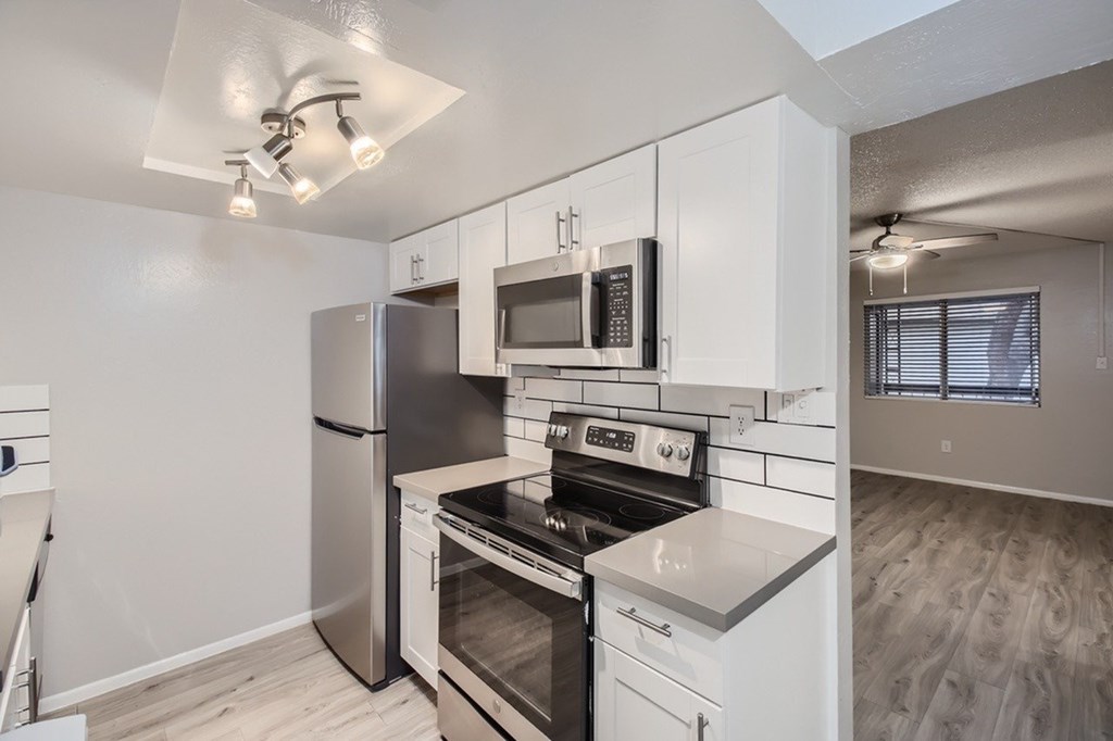 A kitchen with stainless steel appliances and white cabinets.
