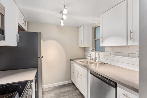A kitchen with white cabinets and a black refrigerator.