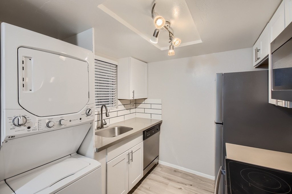 A modern kitchen with white appliances and a black refrigerator.