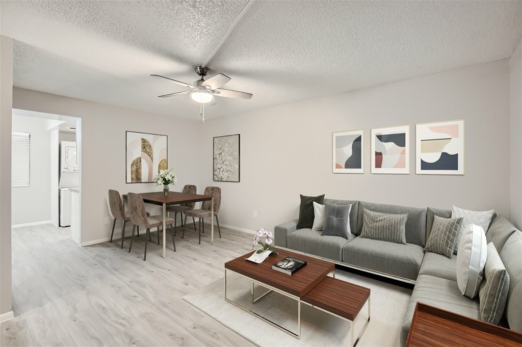 A living room with a grey couch, a wooden coffee table, and a dining table with chairs.