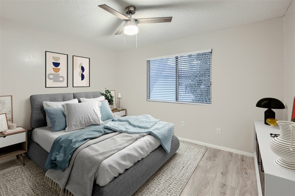 A bedroom with a bed, a ceiling fan, and two framed pictures on the wall.