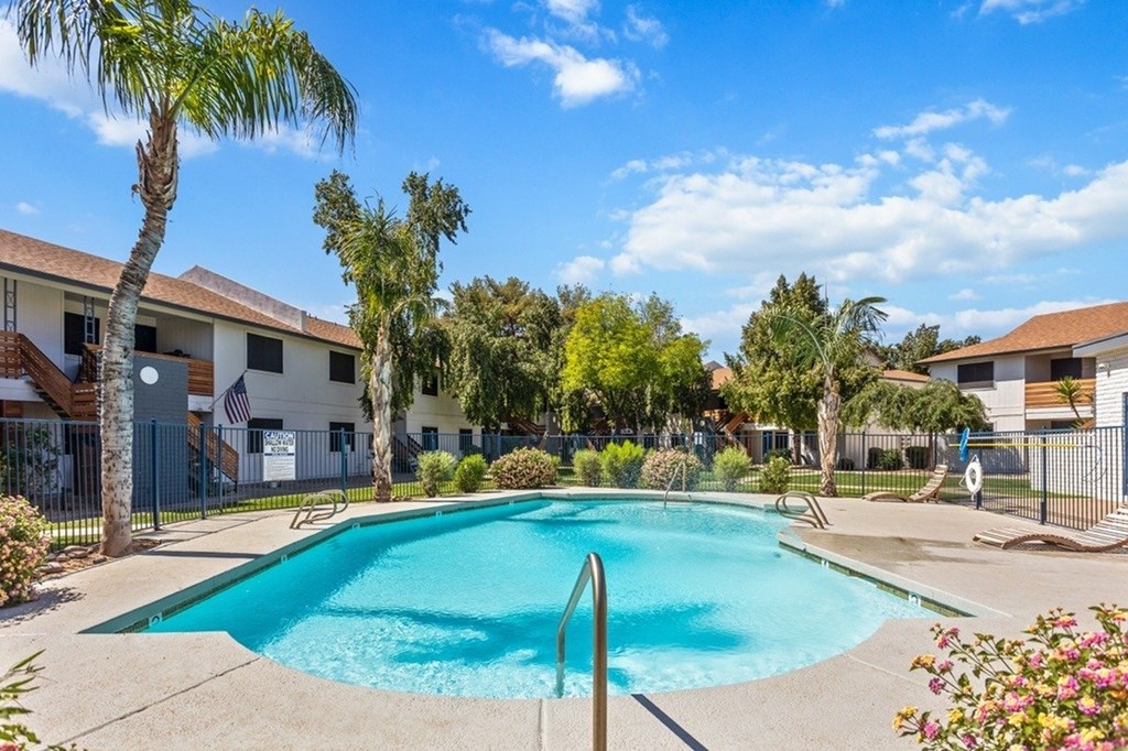 A swimming pool surrounded by palm trees and residential buildings.