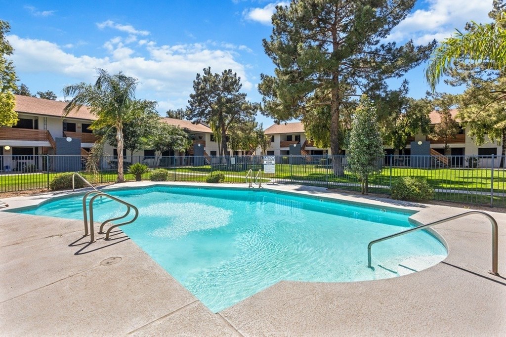 A swimming pool surrounded by a fence and trees.