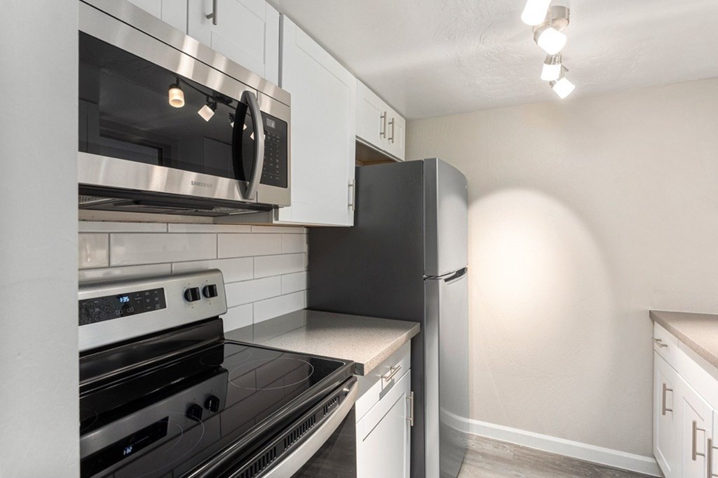 A kitchen with a black refrigerator and stove top oven.