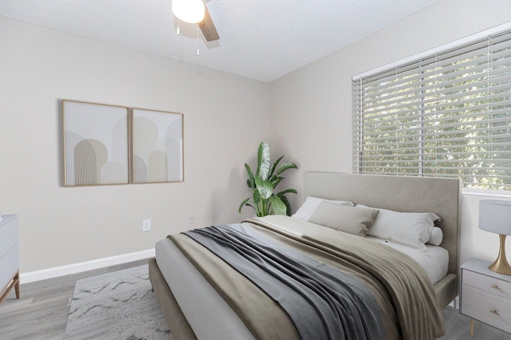 A bedroom with a large bed and a plant on the side table.