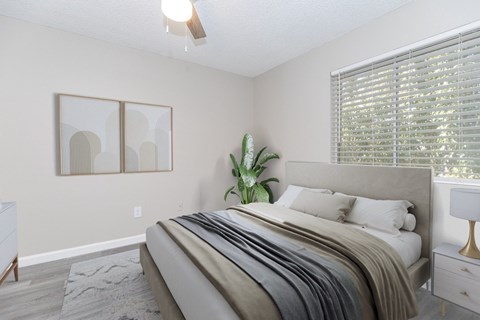 A bedroom with a large bed and a plant on the side table.