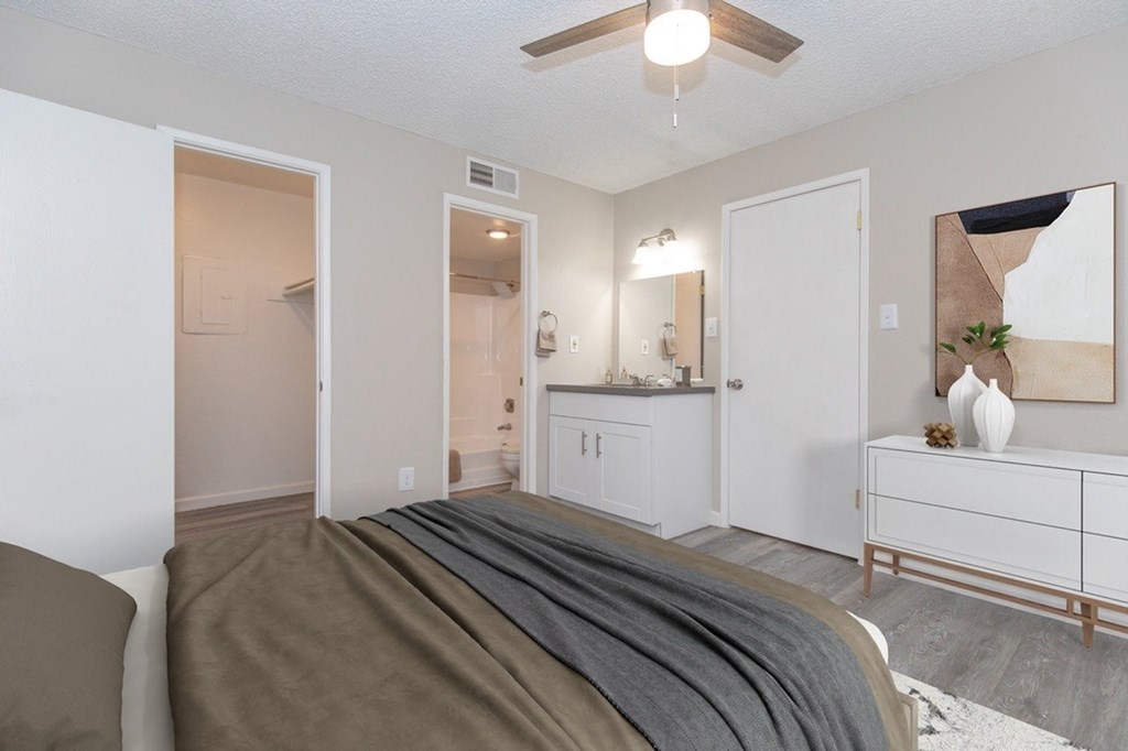 A bedroom with a bed in the foreground and a dresser and mirror in the background.