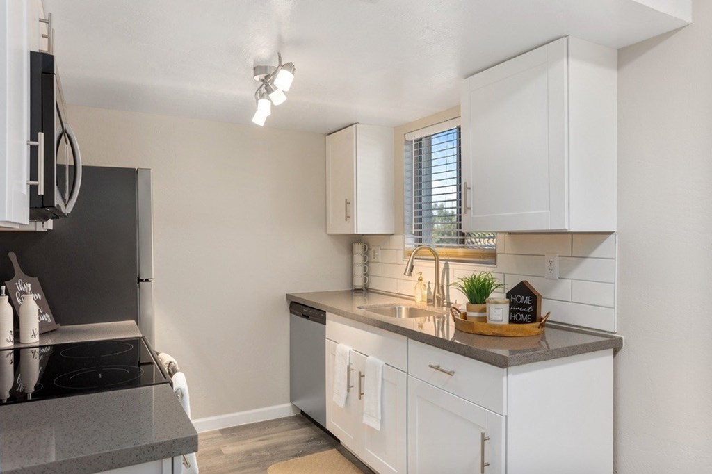 A small, modern kitchen with white cabinets and a black stove top.