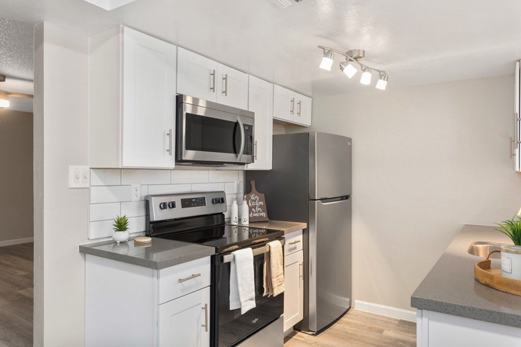 A modern kitchen with white cabinets and stainless steel appliances.