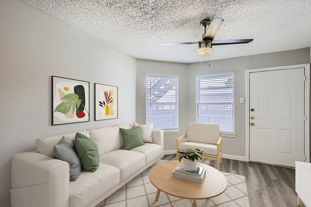 A living room with a white couch, a wooden coffee table, and a ceiling fan.