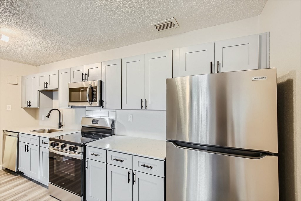 A modern kitchen with a stainless steel refrigerator and white cabinets.