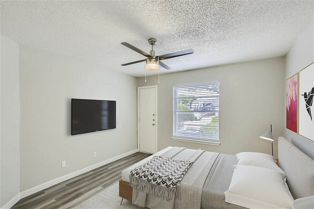 A bedroom with a large bed and a flat screen TV mounted on the wall.